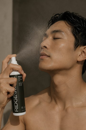 A man with closed eyes holding spraying pre-biotic facial mist on his face, being RESET from Ridge & Rune